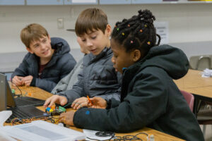 Middle school students work together on a circuit board.