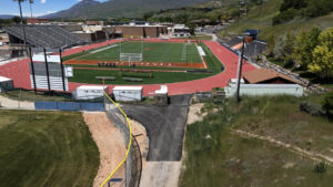 Drone overhead image of football field and concrete walkway leading southwards out of the image