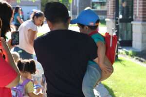 A father carries his preschool son to school.