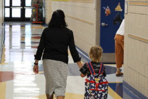 A school administrator walks a student to her class in the hallways.