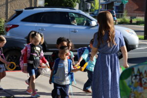 A teacher leads her class into the building on a cute chain of handholds.