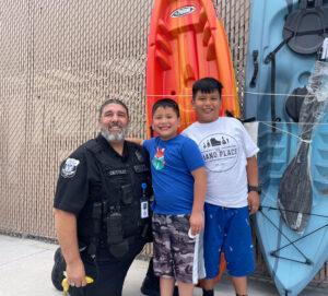 An officer and two boys pose for a photo together in front of Walmart.