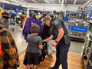 An officer looks at a shirt that one of the boys has picked out.