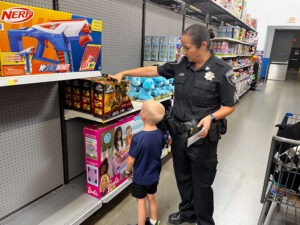 A female officer picks out a toy for a boy.