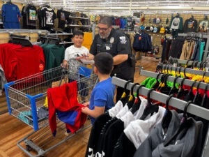 An officer puts clothes in a basket for two young students