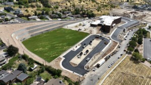 A far exterior drone shot of the Wasatch Elementary school. A grass field and asphalt drop-off exterior lot can be seen.