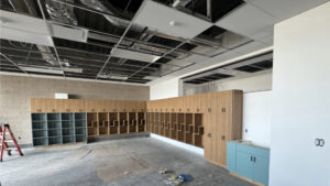 Twenty wooden cabinets line the corner of a classroom wall.