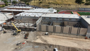 A long drone shot of the north gym reveals that the roof is complete and that the walls of the dance area are enclosed. A crane sits on the bulldozed space in the bottom quadrant of the picture.