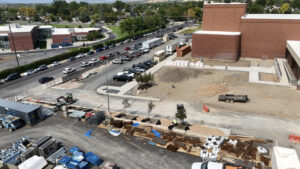 A long drone shot of the southwestern corner of Timpview High School. On the right lays the bulldozed lot, and on the left, concrete sidewalks and newly planted trees. In the far left, across the street, stands Edgemont Elementary.