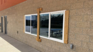 A sliding window attached to the concession stand. A wooden slat is anchored to the masonry, holding the window in place.