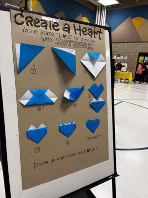 A display for a make-and-take project. It gives step by step directions on creating a heart.