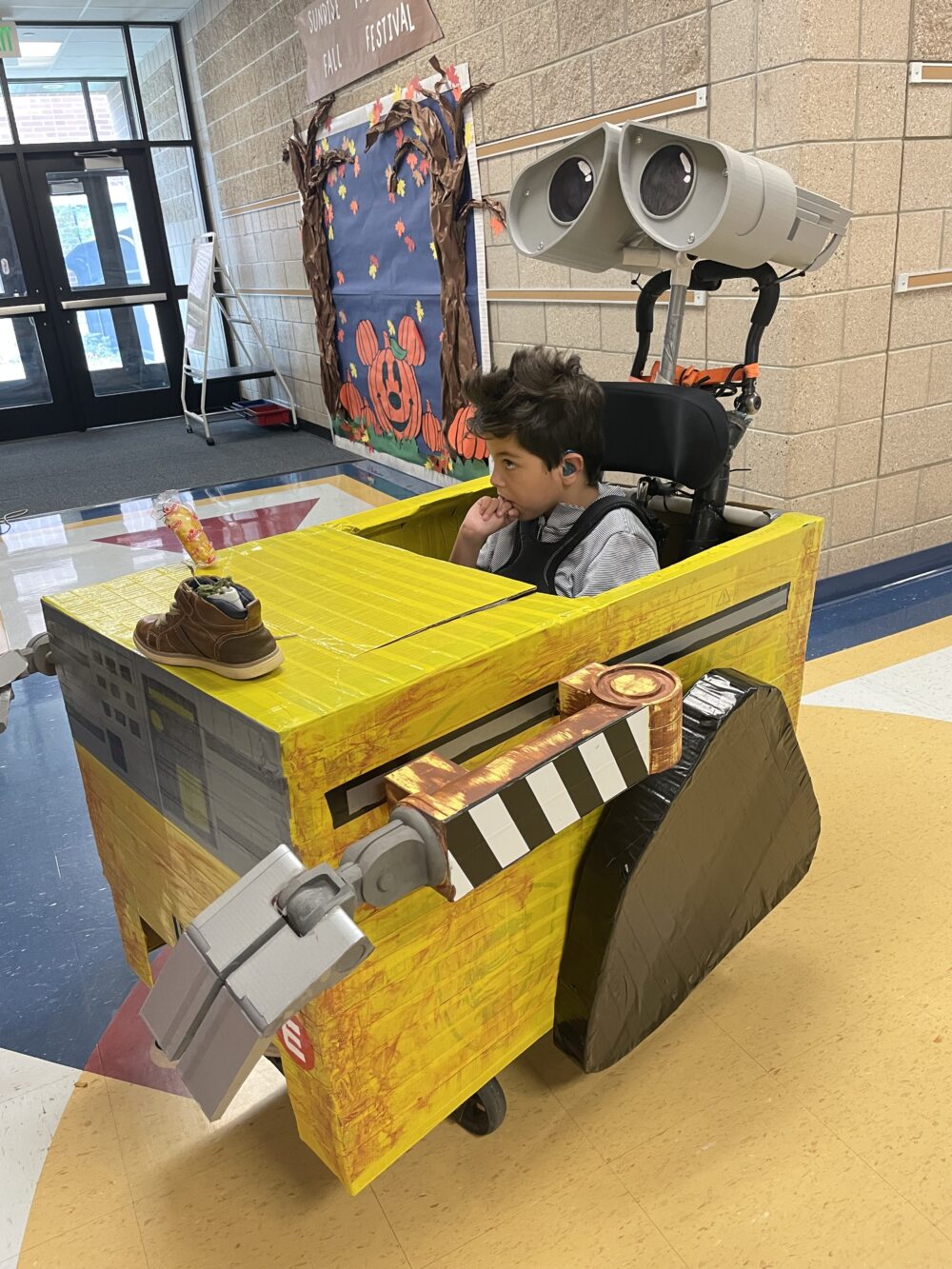 A boy sits in a handmade WALL-E costume, encasing his wheelchair. 