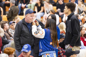 Two student government students are pinning a red poppy on a veteran's jacket.