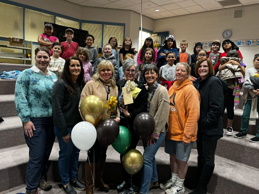 Janett Roberts and Kayleen Dewey stands in the center of a group of students and the Foundation, including Superintendent Dau. 