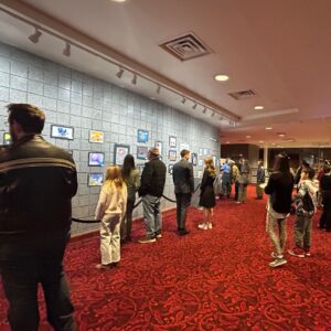 Families and students walk through an art exhibit.