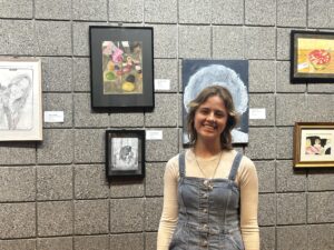 A student stands in front of a painting.