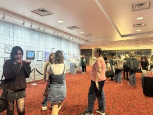 Many people stand in front of a painting gallery.