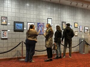 Many people stand in front of a painting gallery.