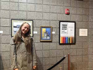 A student stands in front of a painting.