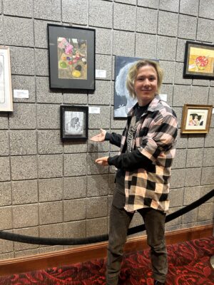 A student stands in front of a painting.