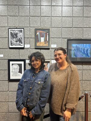 A student and their teacher stand in front of a painting.