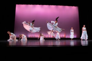 Dancers leap on a stage.