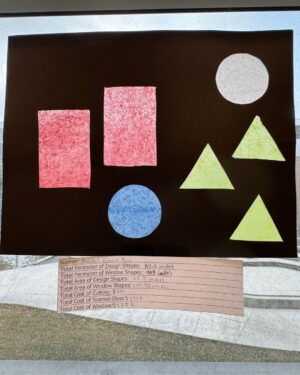 Black paper and red see-through cut-outs glued to the paper are taped to a pane of glass.