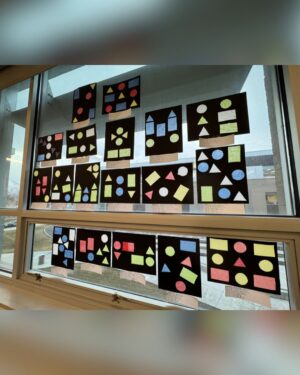 Many black pieces of paper and red see-through cut-outs glued to said paper are taped to a large window.