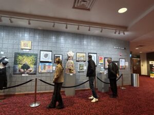 Several students walk along a velvet rope, looking at a gallery hung in the Covey Arts Center.