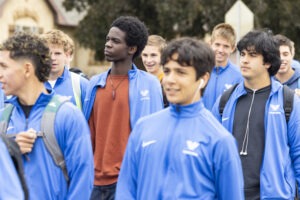 Several boys in blue Nike windbreakers stand in a group.