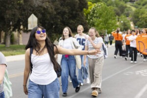 A girl wearing sunglasses waves at the camera.
